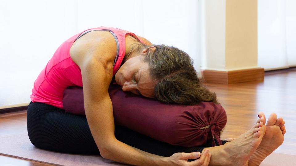 Restorative Yoga Pose: seated forward bend with yoga bolster or pillow