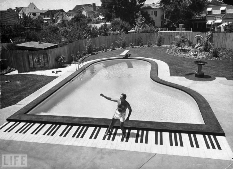 Liberace by his grand piano shaped pool in his backyard in 1954.