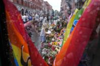 People lay flowers under the rain at the scene of a shooting in central of Oslo, Norway, Sunday, June 26, 2022. Norwegian police say they are investigating an overnight shooting in Oslo that killed two people and injured more than a dozen as a case of possible terrorism. In a news conference Saturday, police officials said the man arrested after the shooting was a Norwegian citizen of Iranian origin who was previously known to police but not for major crimes. (AP Photo/Sergei Grits)