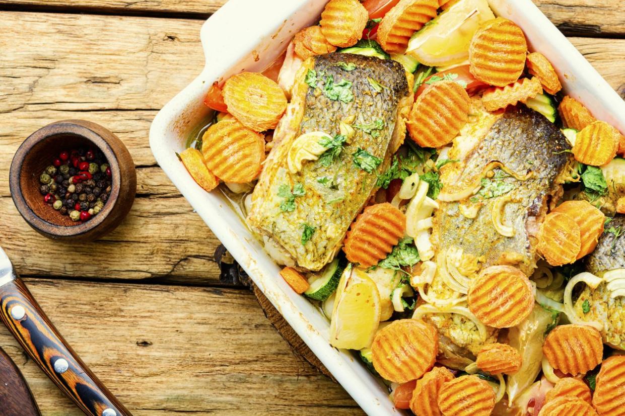 Grilled fish with roasted vegetables in baking dish
