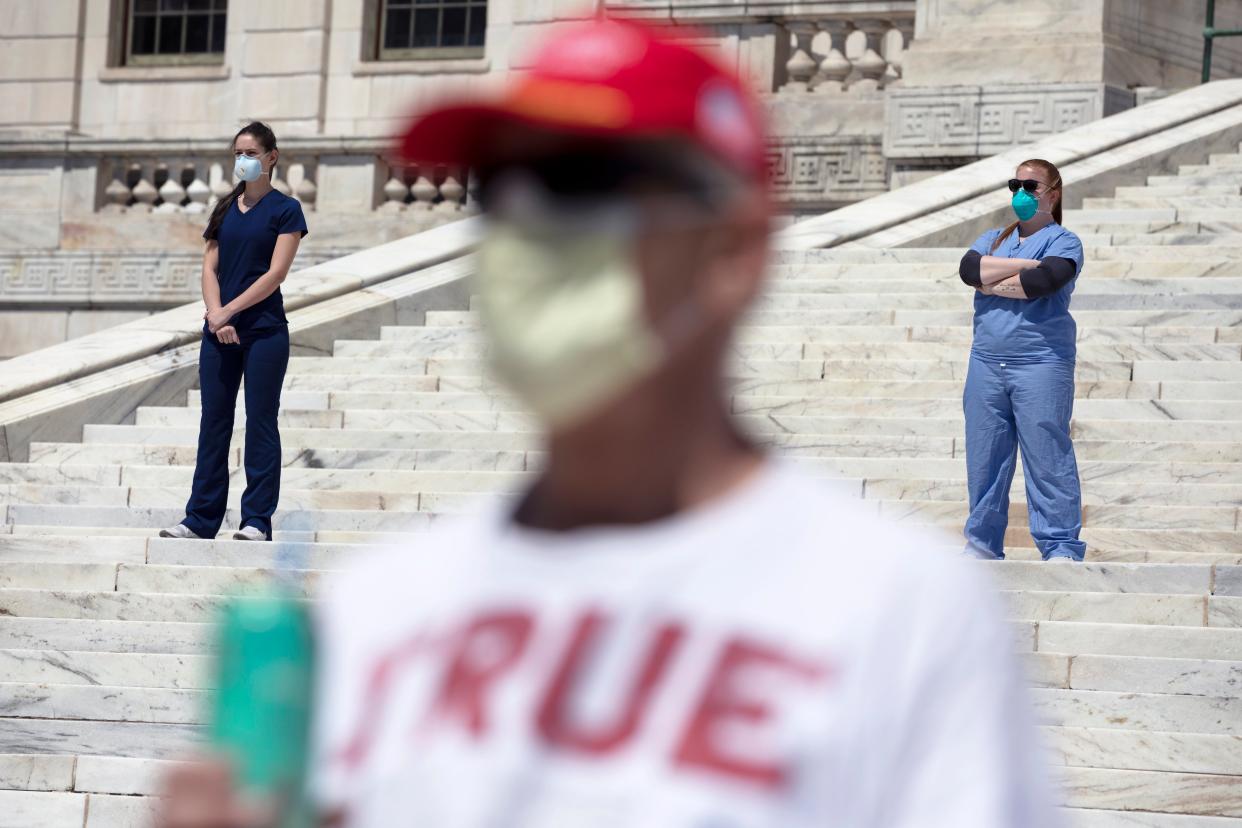 Nurses stand in counter-protest during a demonstration against stay-at-home orders at the State House on Saturday, April 25, 2020, in Providence, R.I., during the coronavirus outbreak.