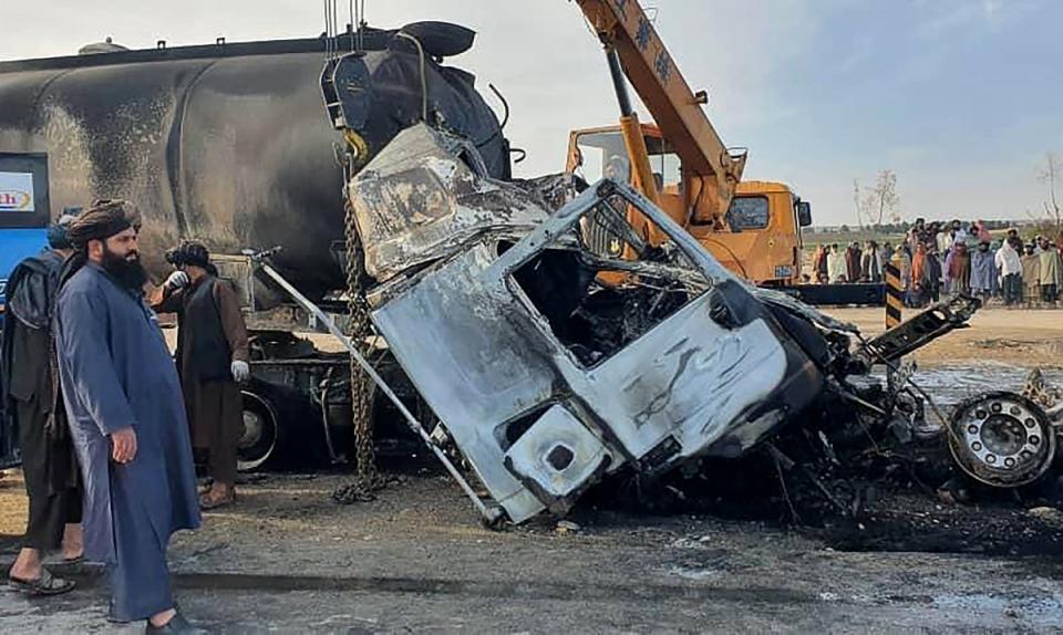 Security personnel and volunteers standing near the wreckage of a burned passenger bus and oil tanker on the Herat-Kandahar highway in the Grishk district of Helmand province (Afghanistan's Helmand Information)