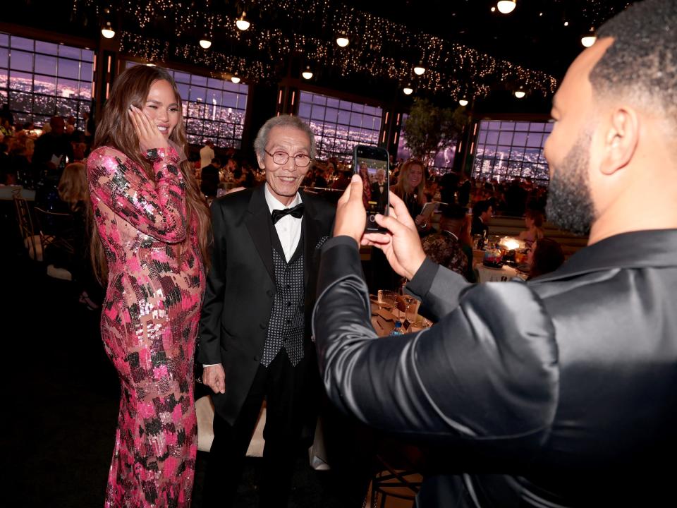 john legend taking a photo of an estatic chrissy teigen and o yeong-su at the emmy