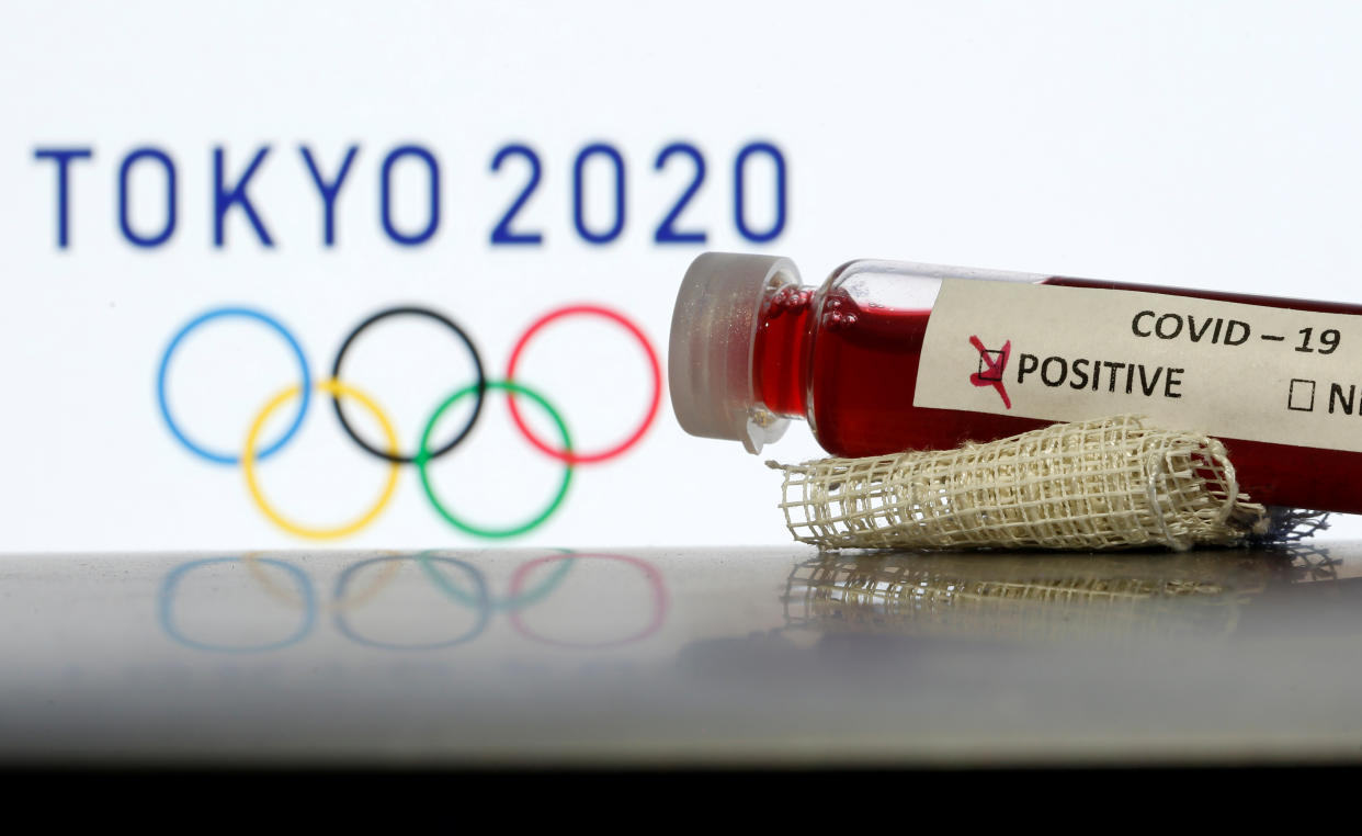 Fake blood in seen in test tubes labelled with coronavirus disease (COVID-19) in front of a displayed Tokyo 2020 Olympics logo in this illustration taken March 19, 2020. REUTERS/Dado Ruvic/Illustration