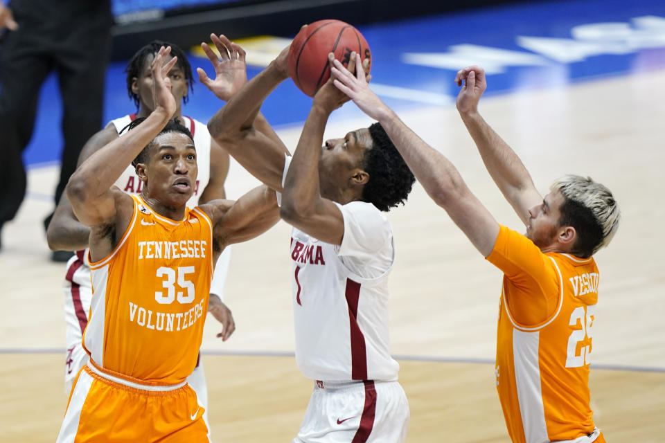 Alabama's Herbert Jones (1) is defended by Tennessee's Yves Pons (35) and Santiago Vescovi (25) in the first half of an NCAA college basketball game in the Southeastern Conference Tournament Saturday, March 13, 2021, in Nashville, Tenn. (AP Photo/Mark Humphrey)
