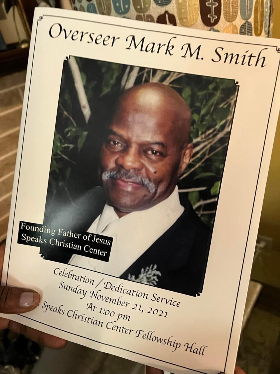 Betty Smith holds a program from the funeral service for her husband Mark M. Smith, who died last summer from COVID-19.