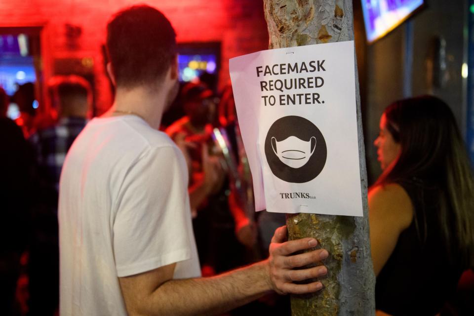 Face mask signage is displayed outside the Trunks bar after midnight early Sunday morning on July 18, 2021 in West Hollywood, California. - Wearing a face mask at indoor public establishments will once again be mandatory in Los Angeles County starting at 11:59 pm July 17, 2021 for both vaccinated and unvaccinated people due to a steady increase in Covid-19 infections and hospitalizations, health authorities said. (Photo by Patrick T. FALLON / AFP) (Photo by PATRICK T. FALLON/AFP via Getty Images)