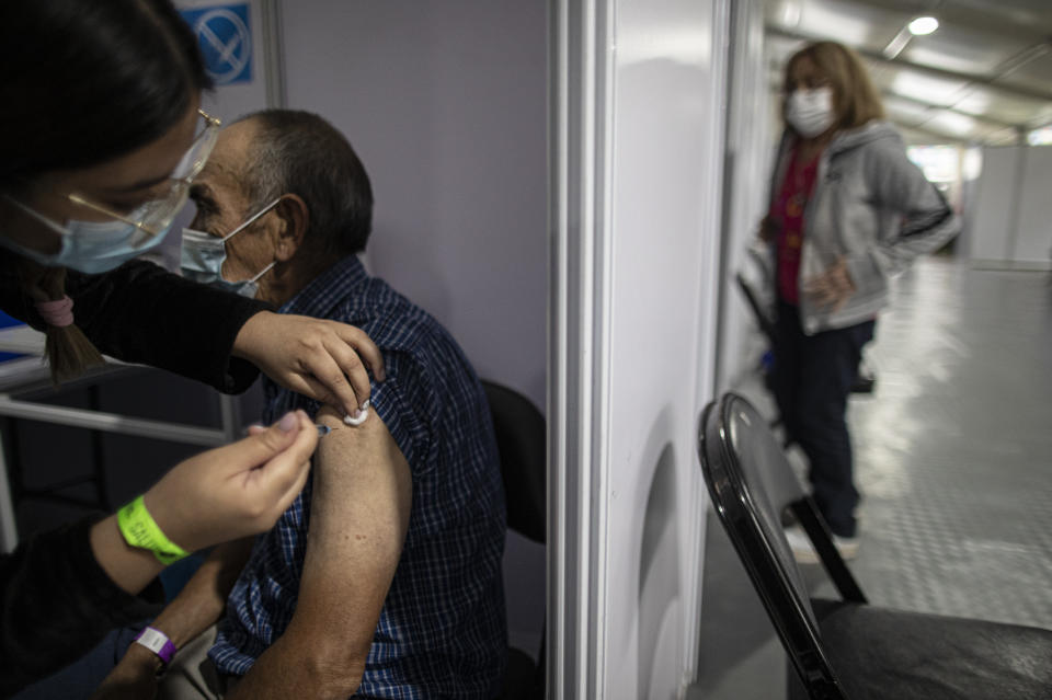 A man receive a a second dose of the Sinovac COVID-19 vaccine at a vaccination center in the Bicentenario Stadium in Santiago, Chile, Thursday, March 18, 2021. Chile has become one of the top countries in the world at vaccinating its population against the new coronavirus. (AP Photo/Esteban Felix)