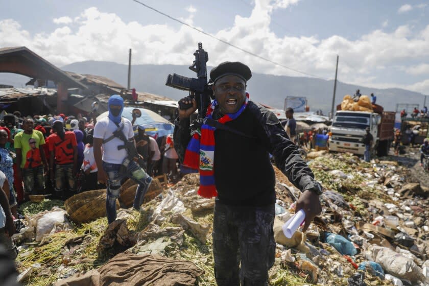 Barbecue, the leader of the "G9 and Family" gang, stands next to garbage to call attention to the conditions people live in as he leads a march against kidnapping through La Saline neighborhood in Port-au-Prince, Haiti, Friday, Oct. 22, 2021. The group said they were also protesting poverty and for justice in the slaying of President Jovenel Moise. (AP Photo/Joseph Odelyn)