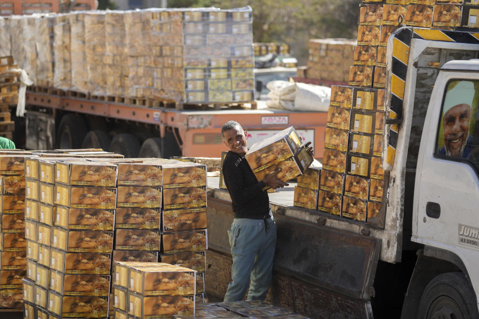 A worker of the Egyptian Food Bank, a non-profit organization specialized in fighting hunger through diversity and innovation, loads boxes of dates donated to Palestinians in the Gaza Strip, at a warehouse in New Cairo, Egypt, Sunday, Feb. 11, 2024. (AP Photo/Amr Nabil)