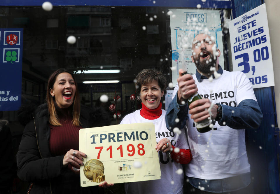 Olivia Muina and her son and daughter, Elena and Javier Castroverde, owners of one of the lottery kiosks that sold the winning number of the biggest prize of Spain's Christmas Lottery, celebrate in Madrid on Friday.&nbsp; (Photo: Susana Vera / Reuters)