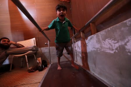 Syrian refugee boy attends a session at a physiotherapy clinic inside a large tent in the border village of Shamarin