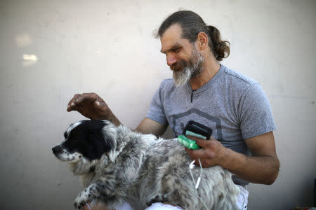 Daniel McMillan, 45, who has been homeless for 20 years, sits with his dog on the street where he lives in Hollywood, Los Angeles, California, U.S. March 29, 2018. Picture taken March 29, 2018. REUTERS/Lucy Nicholson