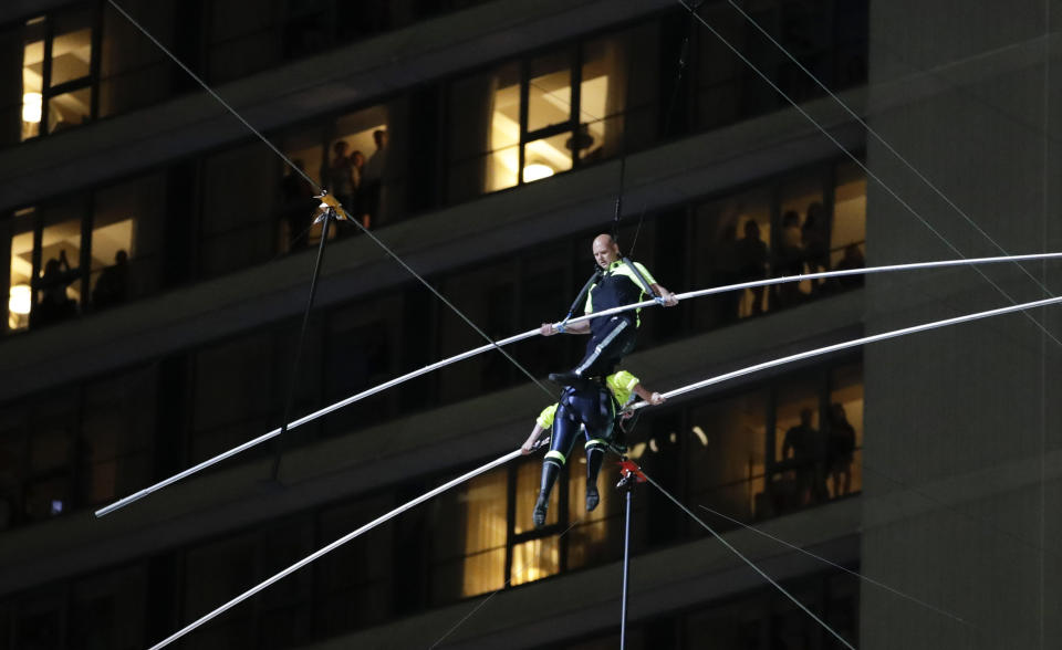 Aerialists Nik Wallenda, top, steps over his sister Lijana as they walk on a high wire above Times Square, Sunday, June 23, 2019, in New York. (AP Photo/Jason Szenes)