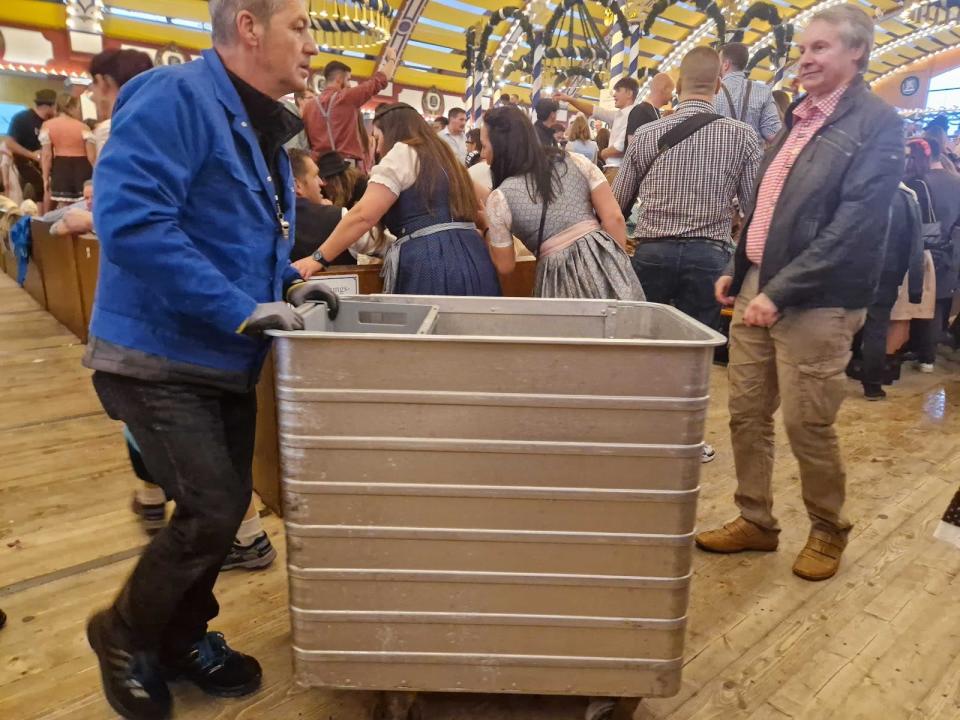 oktoberfest staff pushing metal trolley full of brein and plates