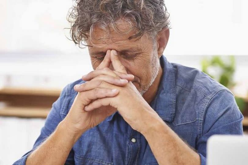 An older man is holding his face in his hands.