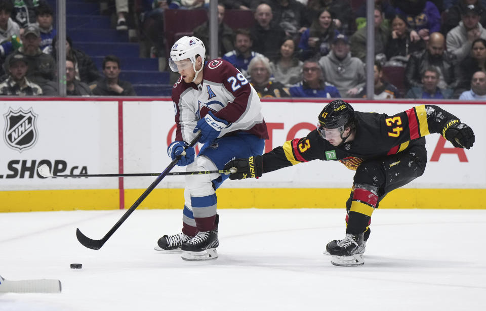 Colorado Avalanche's Nathan MacKinnon (29) skates with the puck past Vancouver Canucks' Quinn Hughes (43) during the second period of an NHL hockey game Friday, Jan. 20, 2023, in Vancouver, British Columbia. (Darryl Dyck/The Canadian Press via AP)