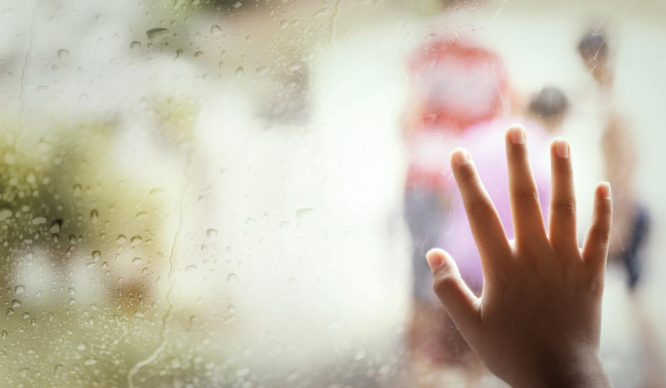 Hand of little girl  by window with raindrops on it on a rainy day.Background.