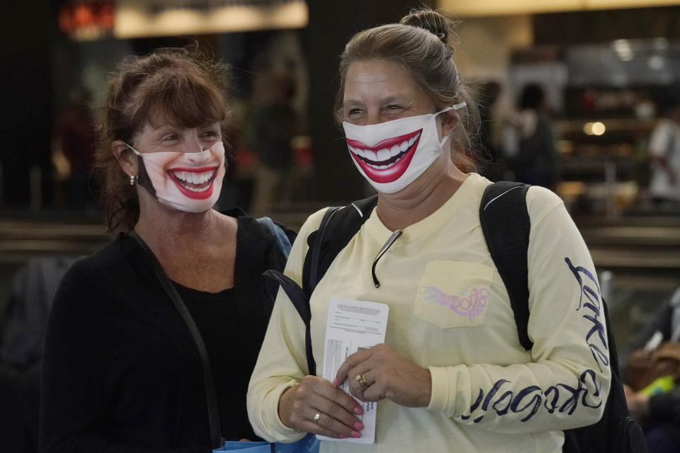 United Airlines passengers Michelle Fehr, left, and Susanne Bartley are interviewed as they wait to board a flight to Hawaii at San Francisco International Airport in San Francisco, Thursday, Oct. 15, 2020. Coronavirus weary residents and struggling business owners in Hawaii will be watching closely as tourists begin to return to the islands on Thursday without having to self-quarantine upon arrival. (AP Photo/Jeff Chiu)