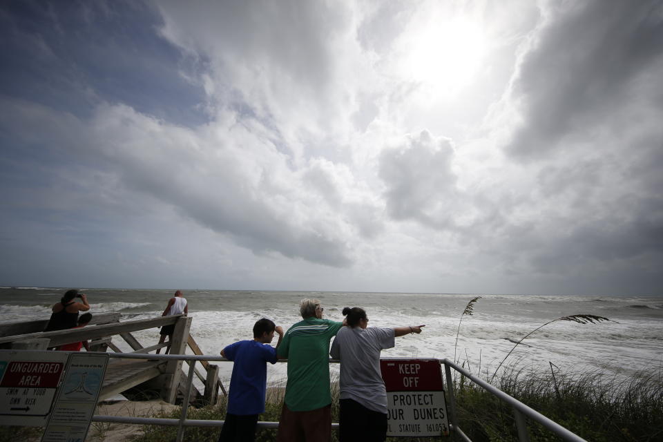 People on a boardwalk look out over the high surf from the Atlantic Ocean, in advance of the potential arrival of Hurricane Dorian, in Vero Beach, Fla., Monday, Sept. 2, 2019. (AP Photo/Gerald Herbert)