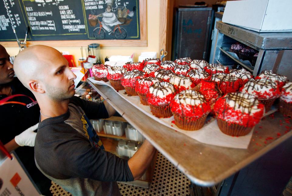 A man with a bald head carries a tray of two dozen cupcakes in 2007 during the grand opening of a Crumbs Bake Shop location in Hollywood, California.