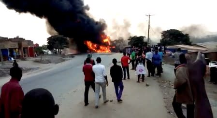 People look towards a fire following a fuel truck collision in Rubirizi