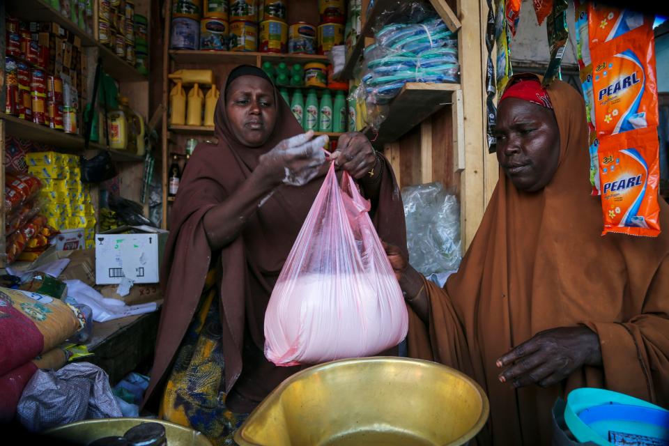 Halimo Hersi, 42, right, buys wheat flour from a shopkeeper in the Hamar-Weyne market in the capital Mogadishu, Somalia Thursday, May 26, 2022.