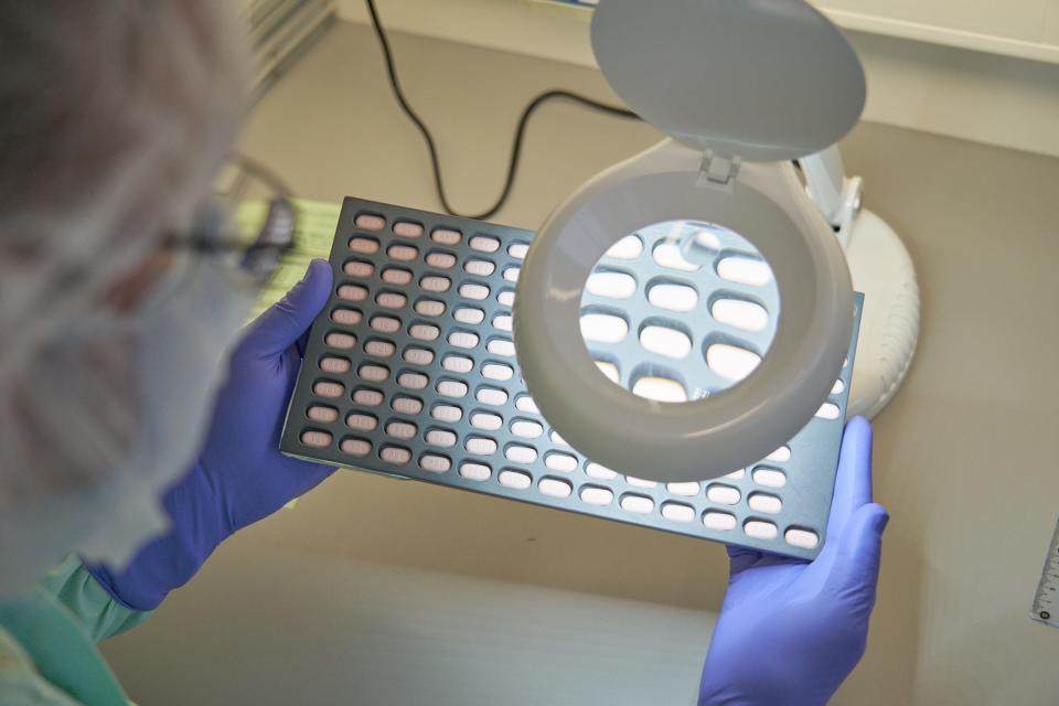 A lab technician examines Paxlovid tablet samples to check for irregularities. It's one of the hundreds of quality checks Pflizer put in place for the production of Paxlovid, its COVID-19 antiviral medication.