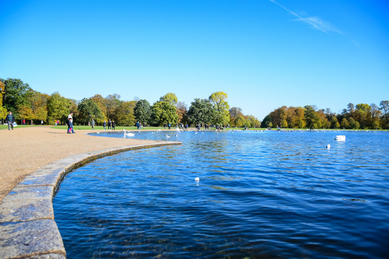 Locals and tourists hanging out at a round pond in front of Kensington Palace, a royal residence in Kensington Gardens, London, England, United Kingdom