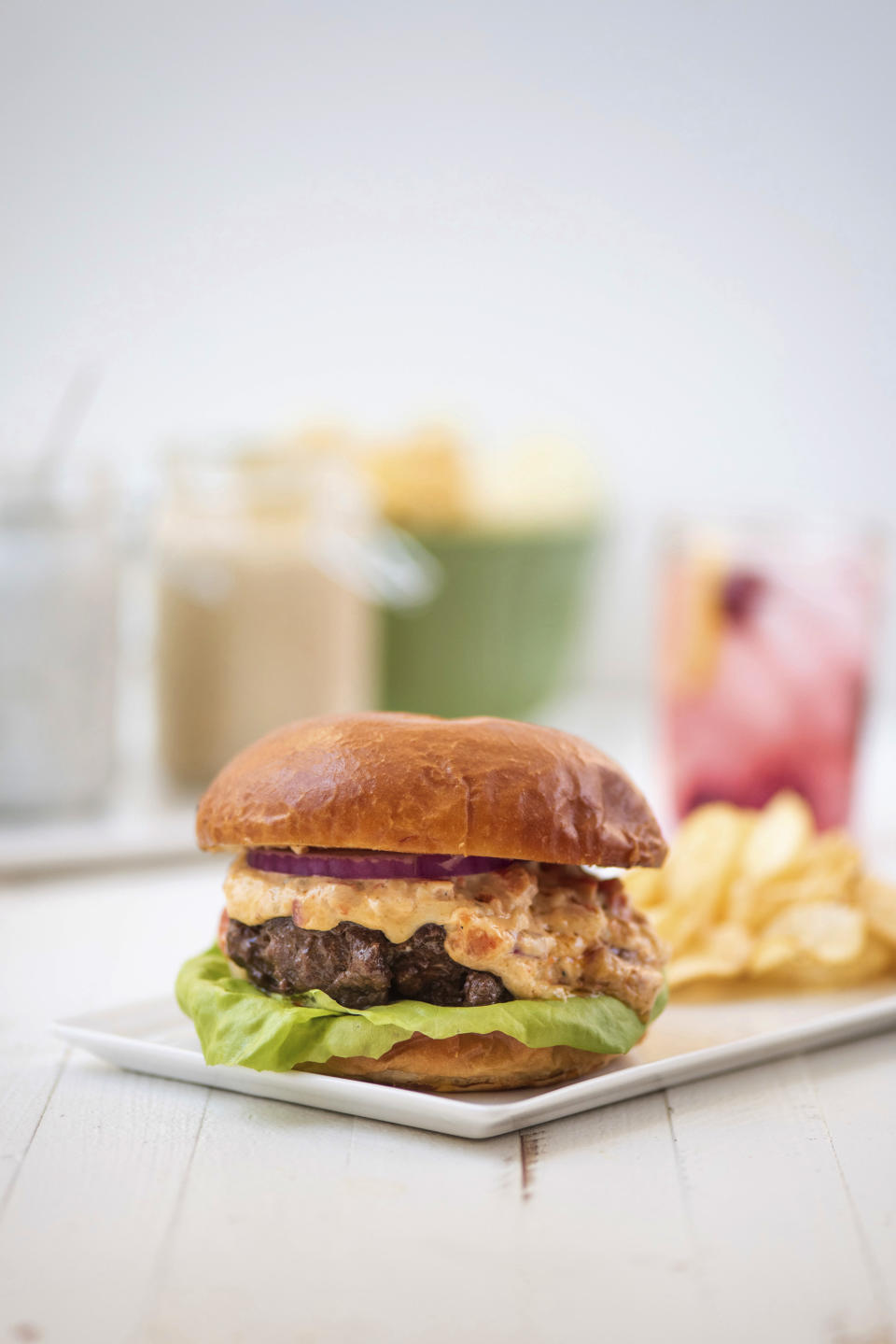 This May 2018 photo shows a burger with pimento cheese in New York. This dish is from a recipe by Katie Workman. (Cheyenne Cohen via AP)