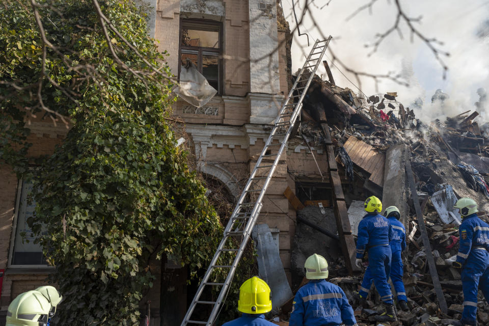 Firefighters work after a drone fired on buildings in Kyiv, Ukraine, Monday, Oct. 17, 2022. Waves of explosive-laden suicide drones struck Ukraine's capital as families were preparing to start their week early Monday, the blasts echoing across Kyiv, setting buildings ablaze and sending people scurrying to shelters. (AP Photo/Roman Hrytsyna)