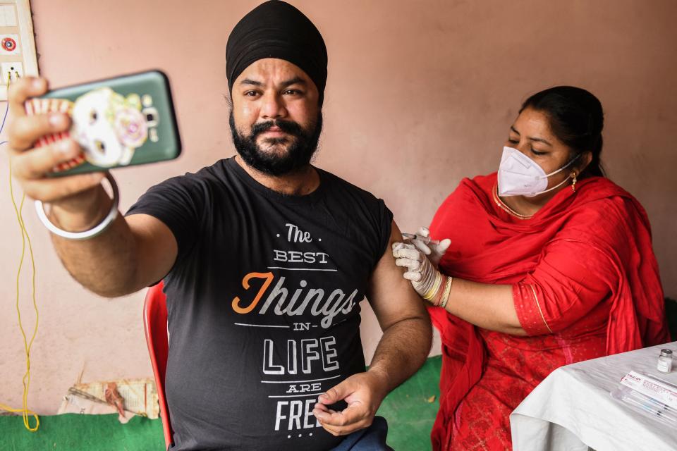 A man takes a selfie while a medical worker inoculates a dose of the Covaxin vaccine in Amritsar (AFP via Getty Images)