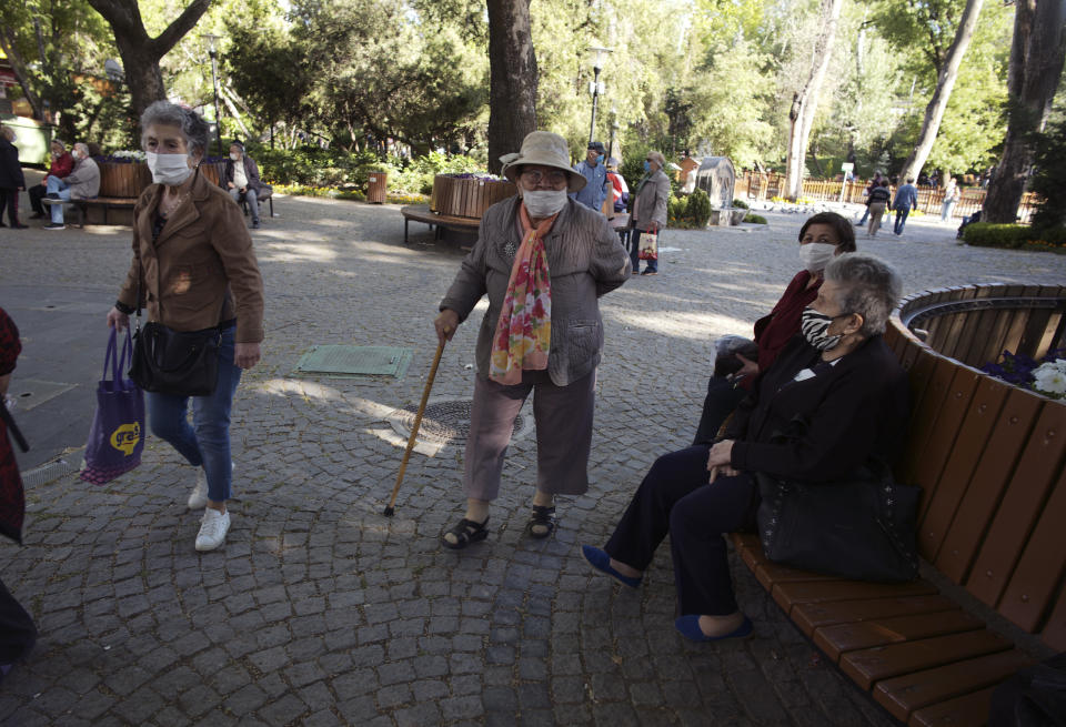 People wearing face masks for protection against the coronavirus, visit a public garden in Ankara, Turkey, Sunday, May 24, 2020, during a four-day curfew declared by the government in an attempt to control the spread of coronavirus. Turkey's senior citizens were allowed to leave their homes for a third time as the country continues to ease some coronavirus restrictions. (AP Photo/Burhan Ozbilici)