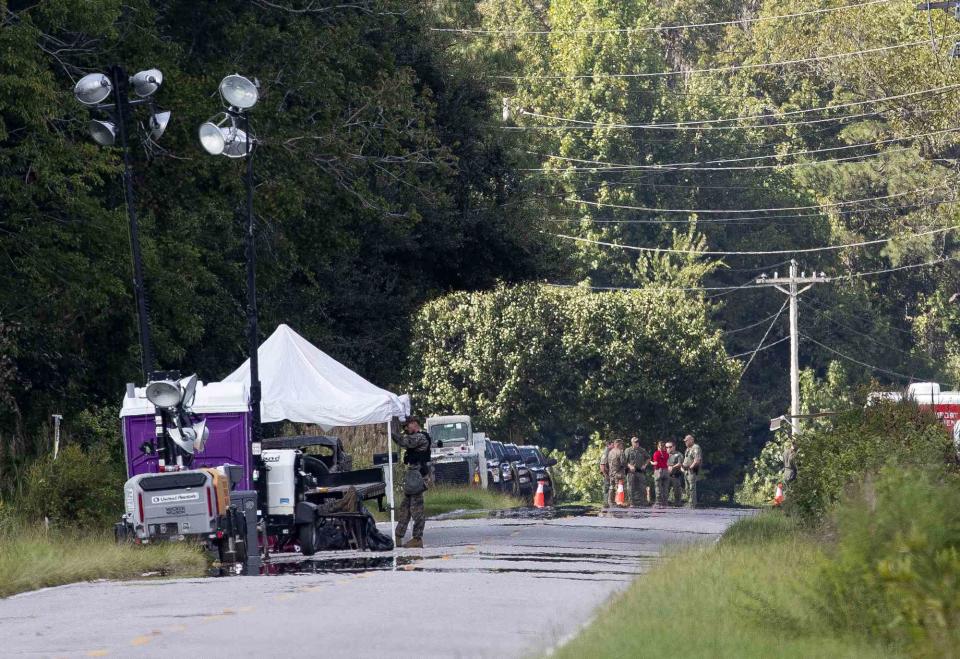 <p>Henry Taylor/The Post And Courier via AP</p> Authorities stand near site of North Carolina fighter jet crash.