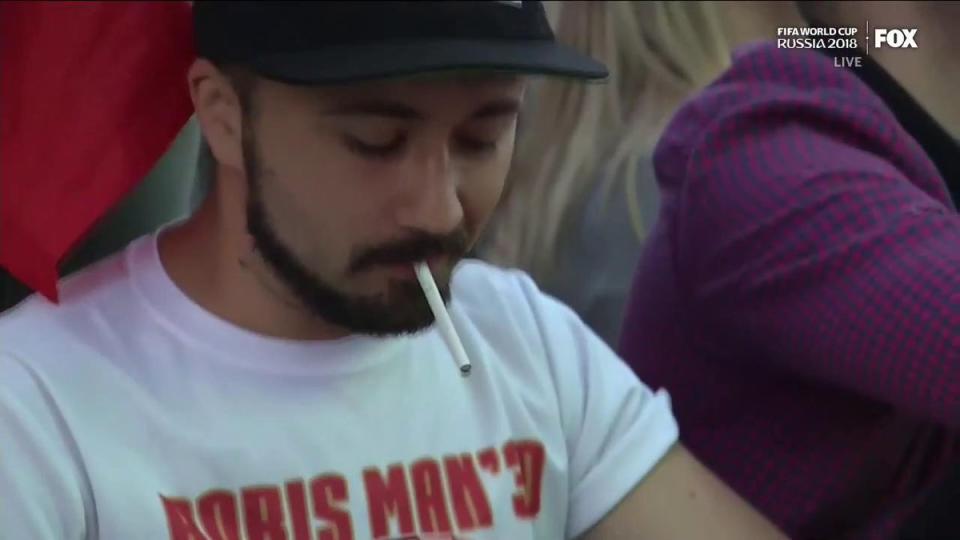 What’s going on with guy using flame wallet to light his cigarette at the World Cup? (Photo via Twitter)