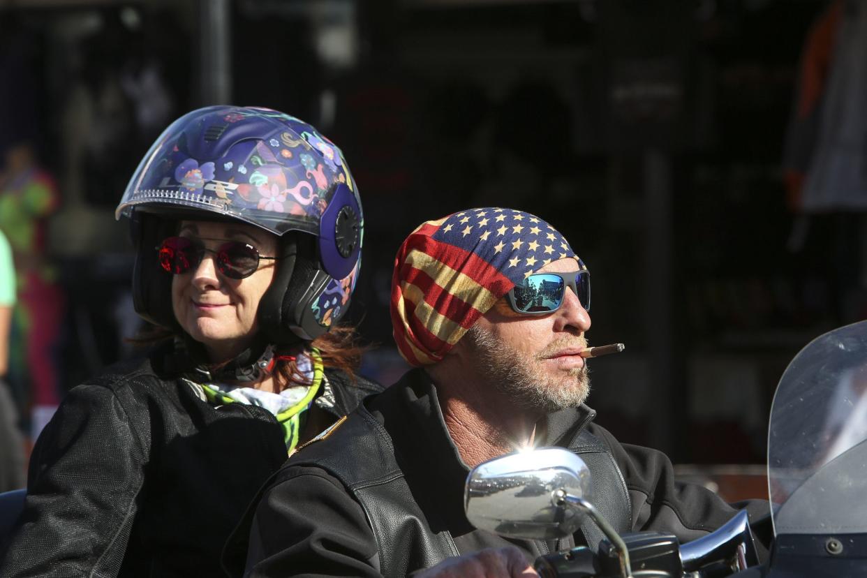 Two people ride down Main Street in Daytona, FL during the start of Bike Week on March 5, 2021. (Sam Thomas/Orlando Sentinel)