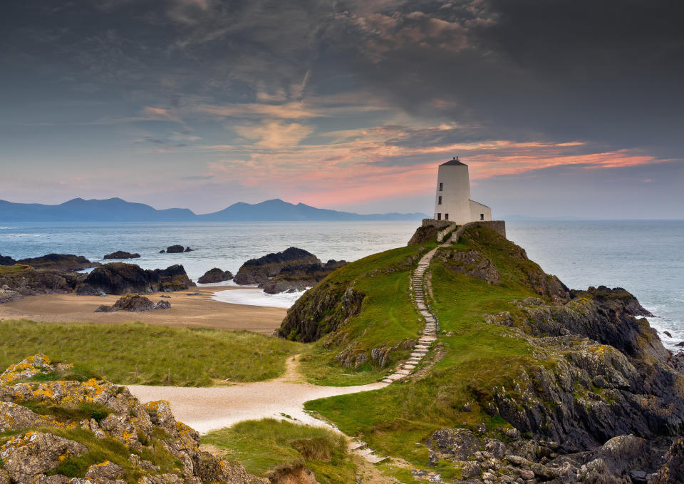 Llanddwyn Lighthouse with Snowdonia mountains in the backdrop.