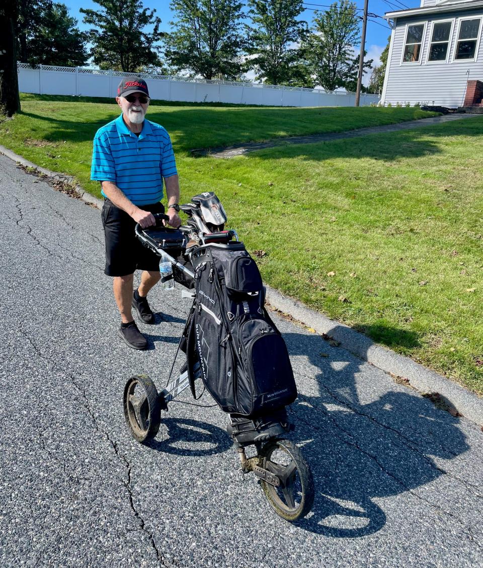 Ed Gibbons pushes his golf cart home down Marsh Avenue after playing a round at Green Hill.