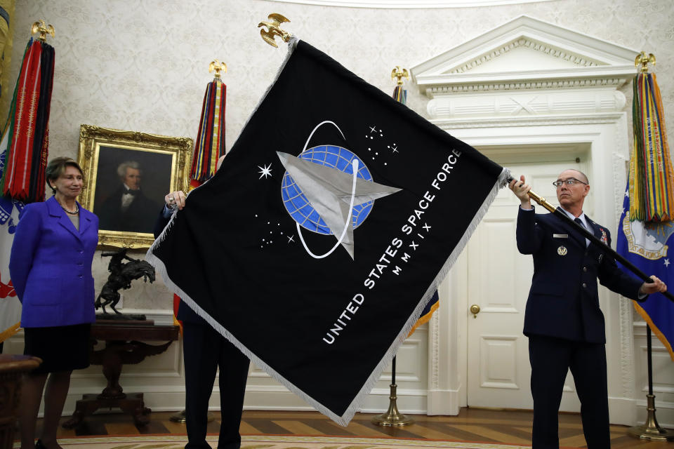 Secretary of the Air Force Barbara Barrett, left, watches Chief Master Sgt. Roger Towberman holds the United States Space Force flag as it is presented in the Oval Office of the White House, Friday, May 15, 2020, in Washington.  (AP Photo/Alex Brandon)