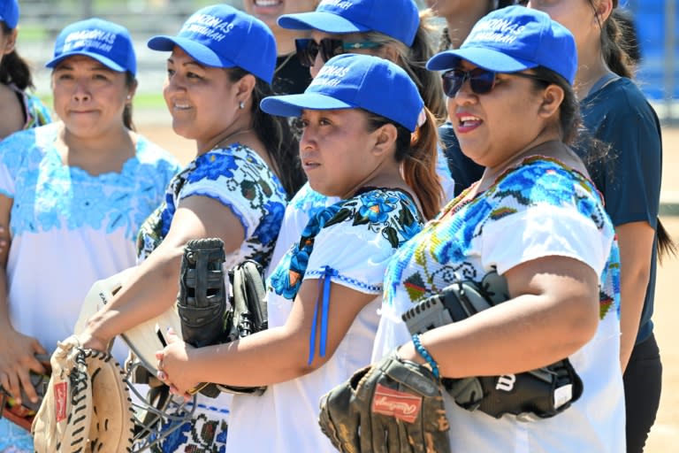 Des membres de "Las Amazonas de Yaxunah", une équipe féminine de softball de la région du Yucatan, au Mexique, jouant pieds nus et en robes traditionnelles, participent à un match amical contre l'équipe féminine de softball du lycée de Walnut, le 31 mai 2024 en Californie (Robyn Beck)