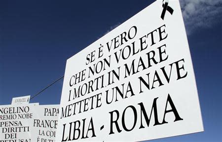 A sign that reads, " If it's true that you don't want dead bodies in the sea, introduce a ferry from Libya to Rome," is seen as European Commission President Jose Manuel Barroso and Italy's Prime Minister Enrico Letta arrive in Lampedusa October 9, 2013. REUTERS/Calogero Lampo