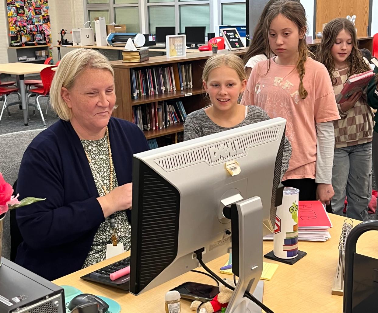 Johnstown Intermediate School librarian Brandie Peterman helps fifth-grader Addie Schmitz check out a book on Wednesday.