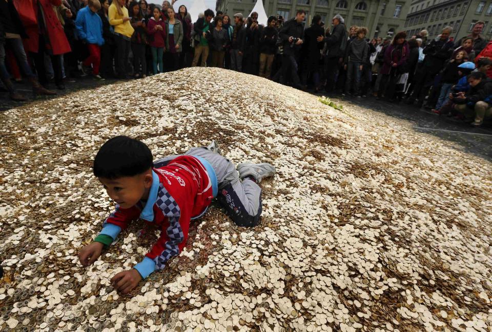 A child plays on a pile of 8,000,00 five cent coins in the centre of the Federal Square during an event organised by the Committee for the initiative Grundeinkommen in Bern