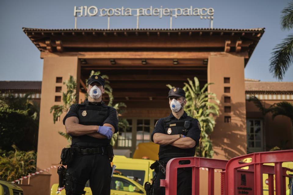 Police officers wearing masks stand in front of the H10 Costa Adeje Palace hotel in La Caleta, in the Canary Island of Tenerife, Spain, Wednesday, Feb. 26, 2020. Spanish officials say a tourist hotel on the Canary Island of Tenerife has been placed in quarantine after an Italian doctor staying there tested positive for the COVID-19 virus and Spanish news media says some 1,000 tourists staying at the complex are not allowed to leave. (AP Photo)