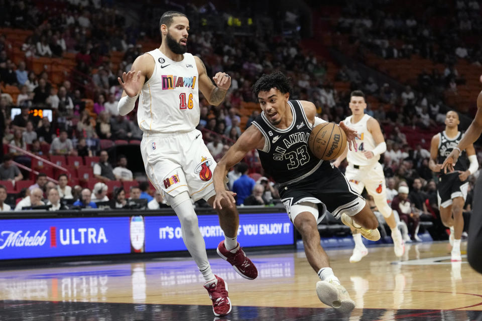 San Antonio Spurs guard Tre Jones (33) drives to the basket as Miami Heat forward Caleb Martin (16) defends during the first half of an NBA basketball game, Saturday, Dec. 10, 2022, in Miami. (AP Photo/Lynne Sladky)