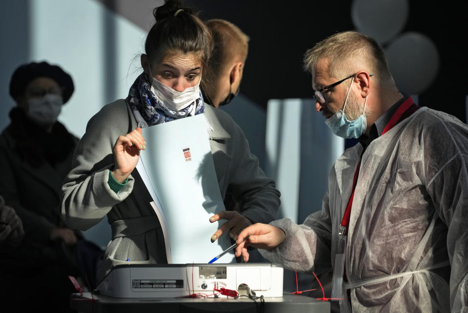 A member of an election commission helps to a woman to casts her ballot during the State Duma, the Lower House of the Russian Parliament and local parliament elections at a polling station in St. Petersburg, Russia, Sunday, Sept. 19, 2021. The head of Russia's Communist Party, the country's second-largest political party, is alleging widespread violations in the election for a new national parliament in which his party is widely expected to gain seats. (AP Photo/Dmitri Lovetsky)