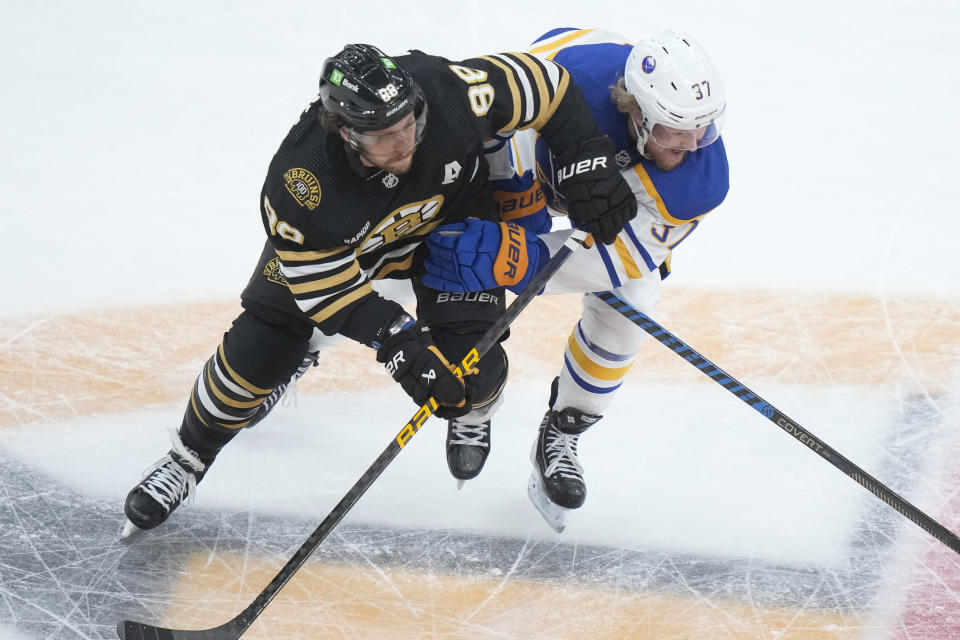 Boston Bruins right wing David Pastrnak (88) and Buffalo Sabres center Casey Mittelstadt (37) work for position in the first period of an NHL hockey game Thursday, Dec. 7, 2023, in Boston. (AP Photo/Steven Senne)