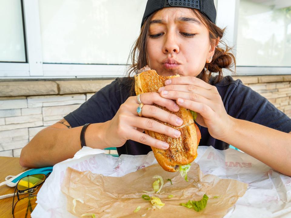 The author chews a bite of her hoagie from Wawa at a table outside.