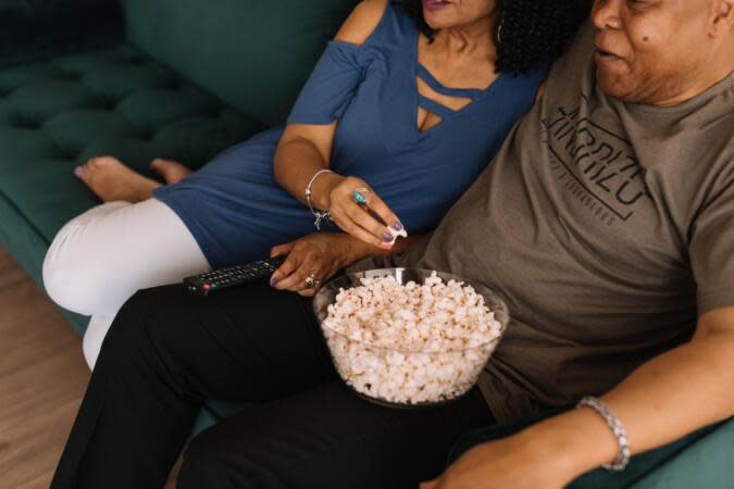 Countdown to Christmas with this list of The 12 Days of Black Christmas Movies. Pictured: a husband and wife on the couch with some popcorn. | 