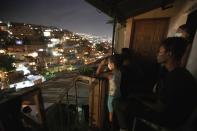 La gente observa la cinta Aladdin, que es proyectada en una pantalla colocada en el techo de un hogar en la barriada de Petare en Caracas, Venezuela, el lunes 1 de junio de 2020. (AP Foto/Ariana Cubillos)